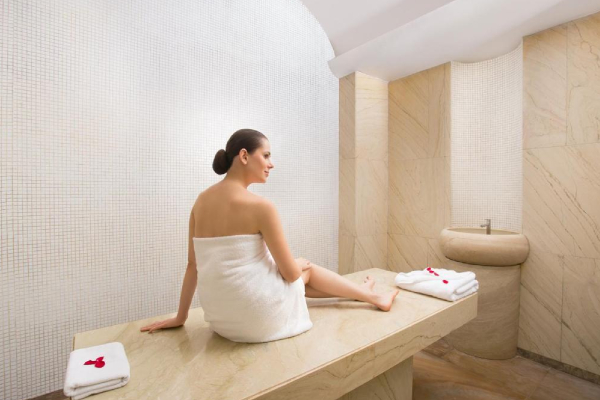 A woman wrapped in a towel relaxes on a marble slab